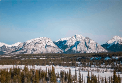 Imagem de um vale coberto por neve e ao fundo belas montanhas e um céu azul
